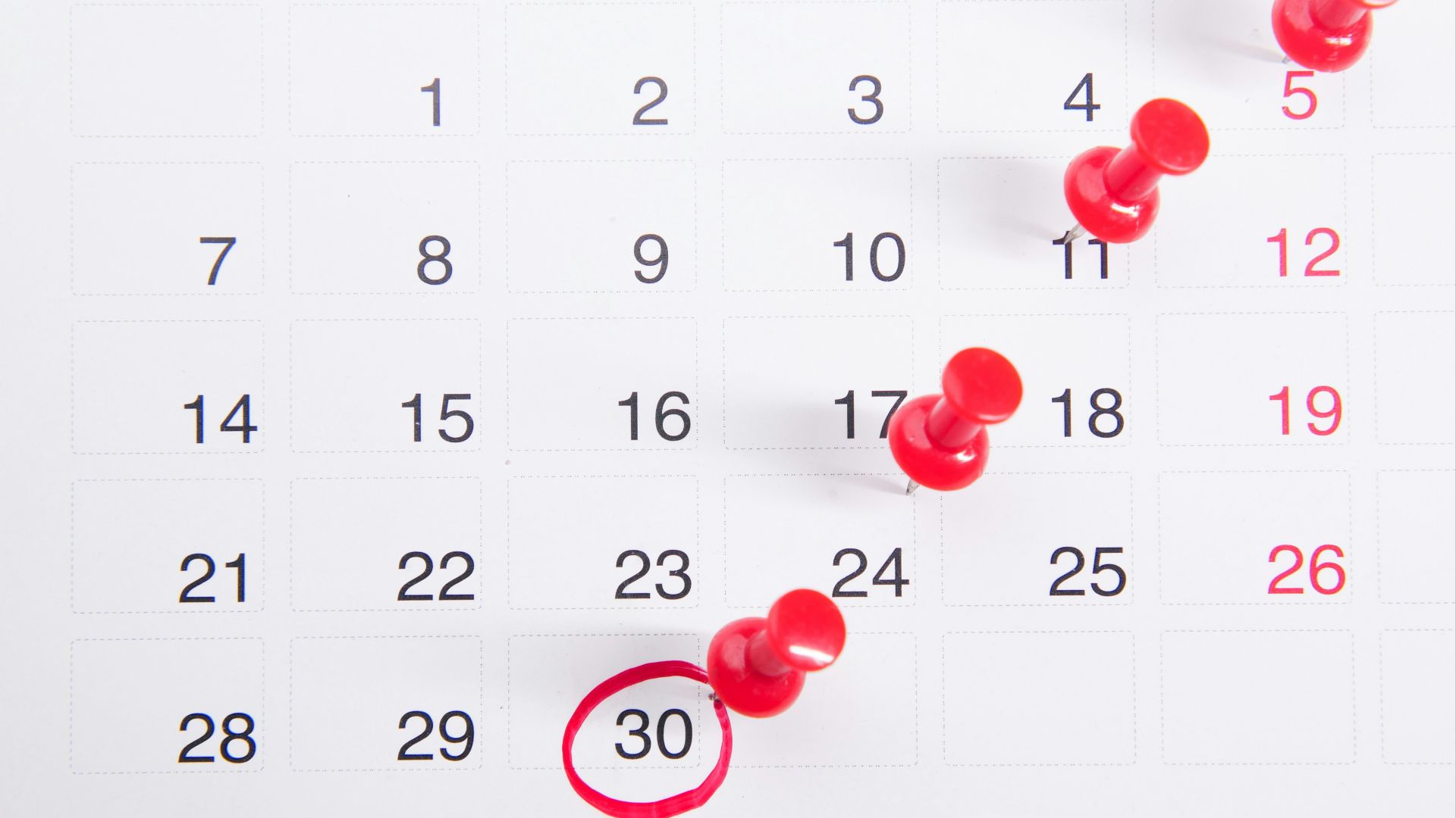 a calendar with red push buttons pinned to it