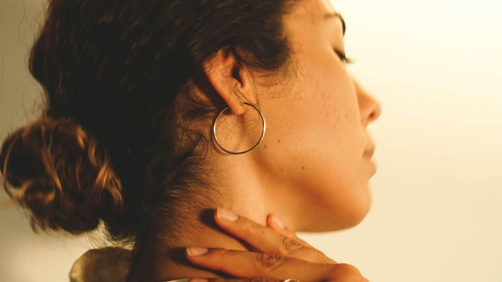 a woman wearing a white shirt and gold hoop earrings