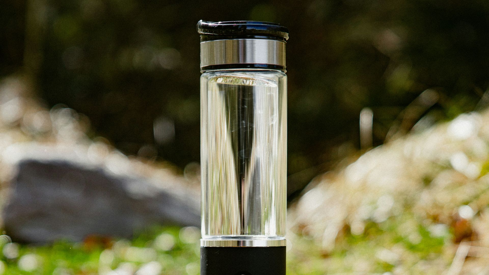 a glass water bottle sitting on top of a rock