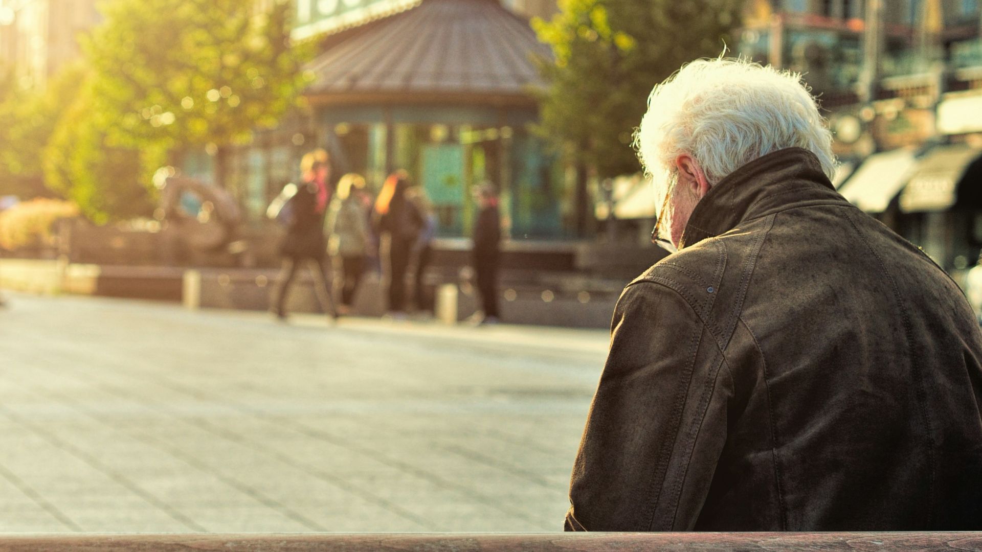man sitting on brown wooden bench