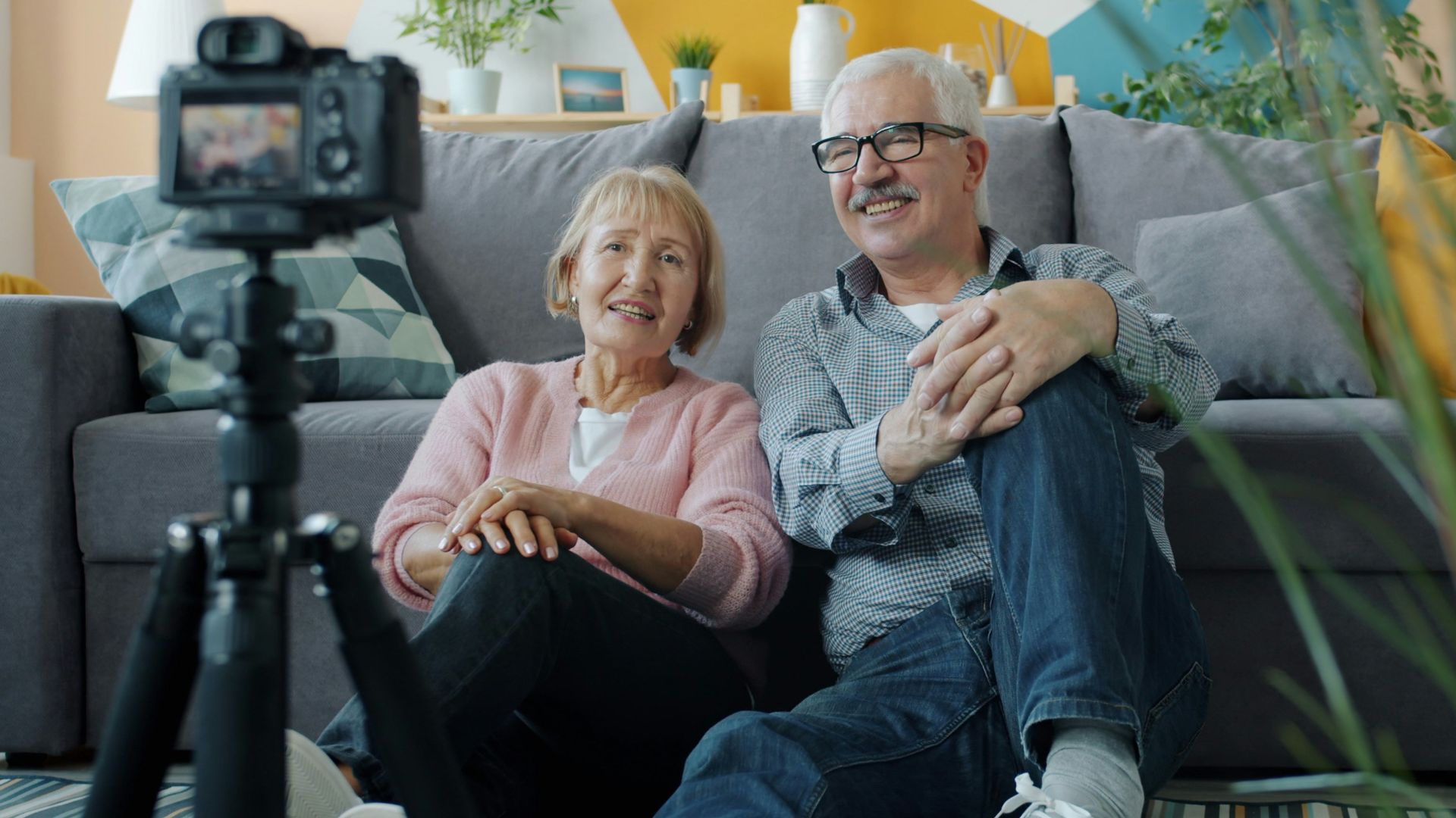 Elderly couple smiling at camera in-home video camera setup.