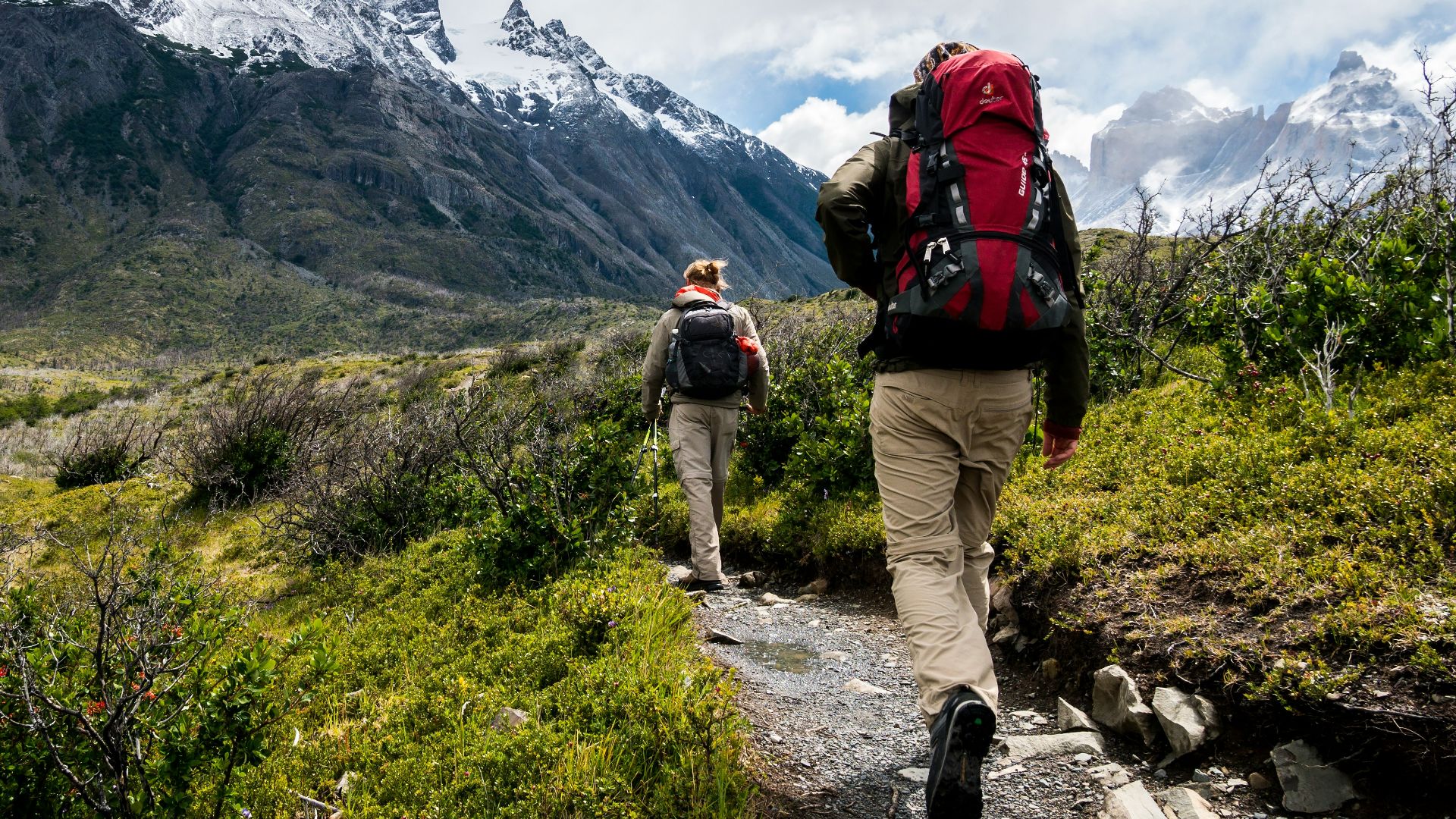 two person walking towards mountain covered with snow