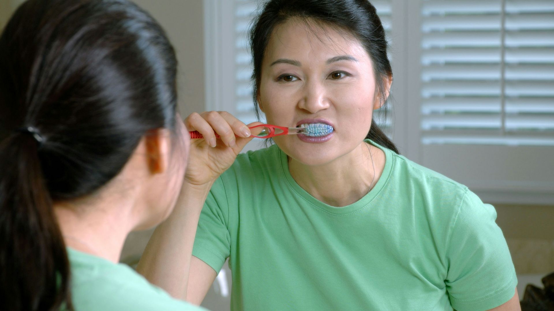 woman in green crew neck shirt holding red lollipop