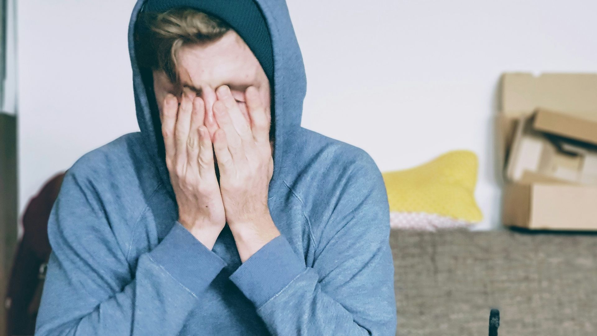 man covering face with both hands while sitting on bench
