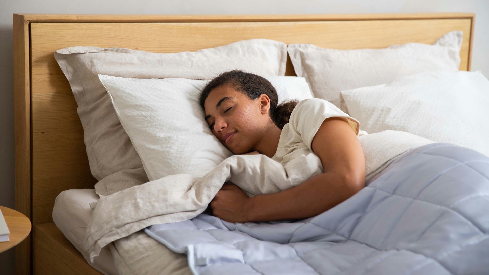 a young girl sleeping in a bed with white sheets