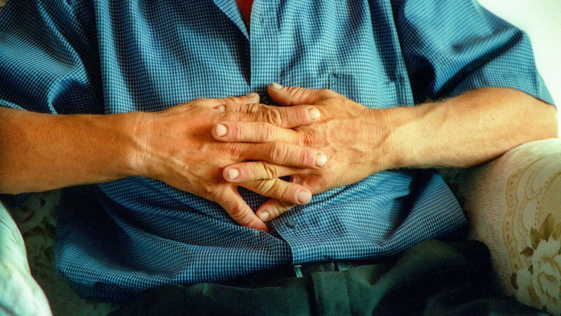 a man sitting on a couch holding his hands together