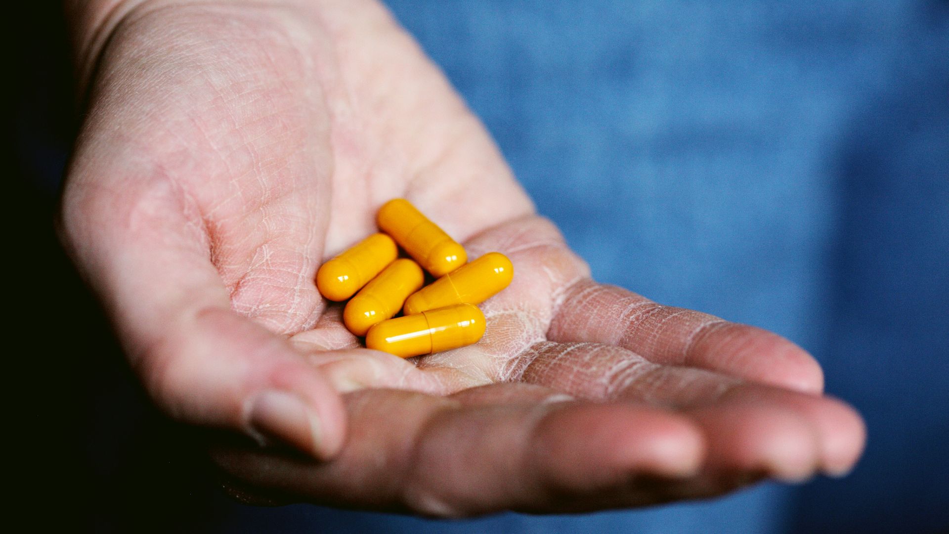 yellow medication pill on persons hand