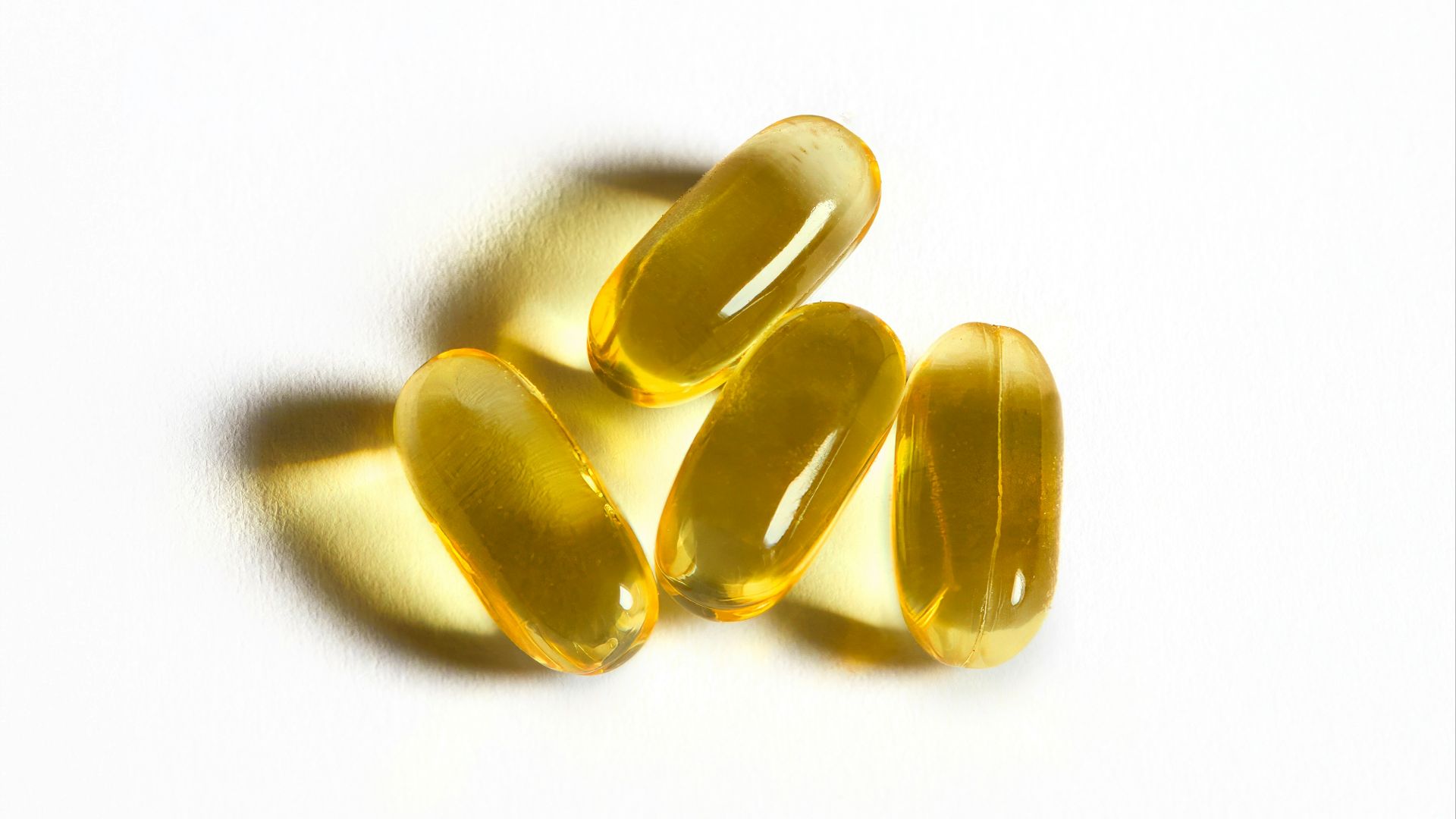 Four yellow capsules sit on a white surface.