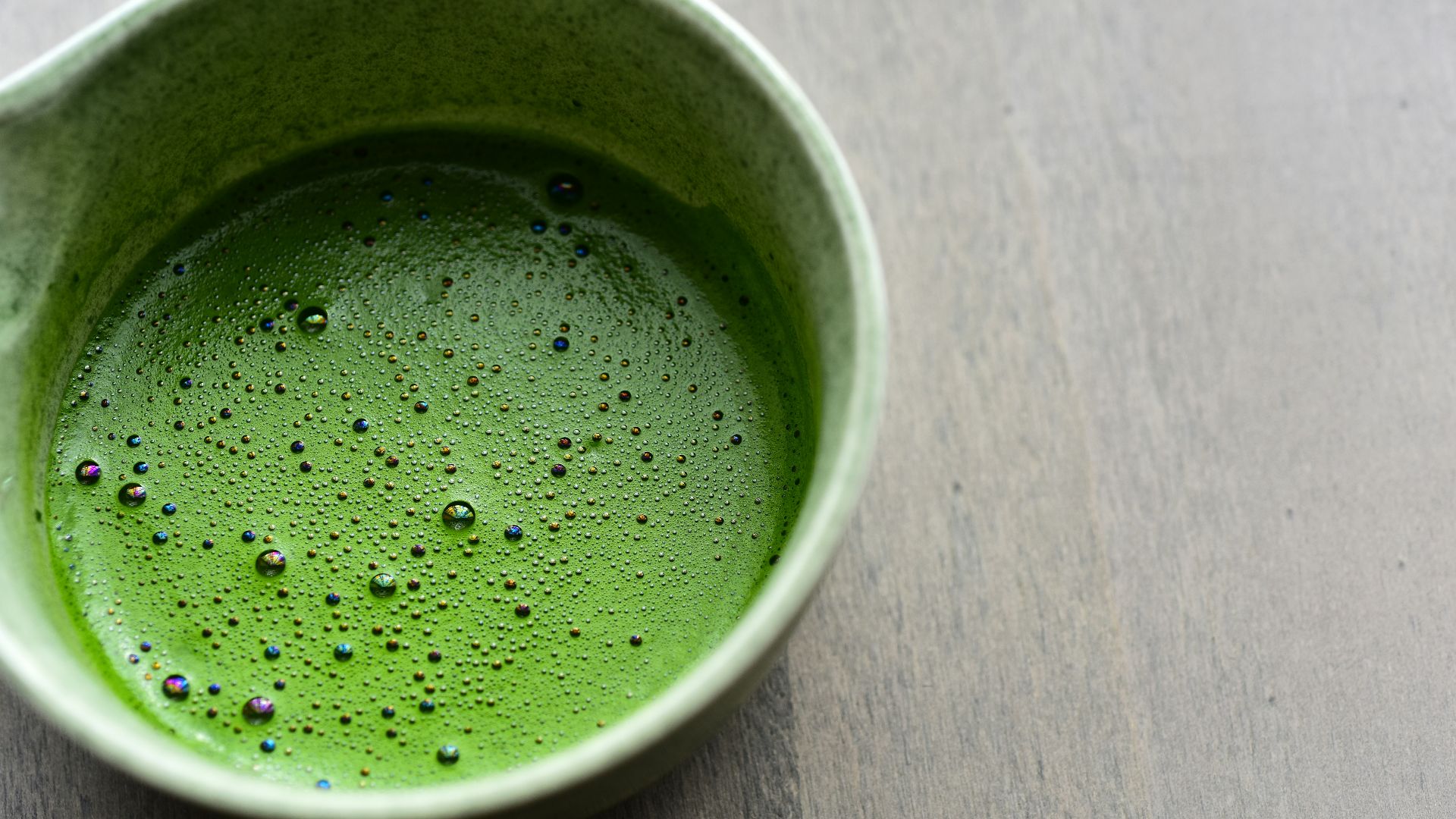 A cup of frothy, vibrant green matcha tea.