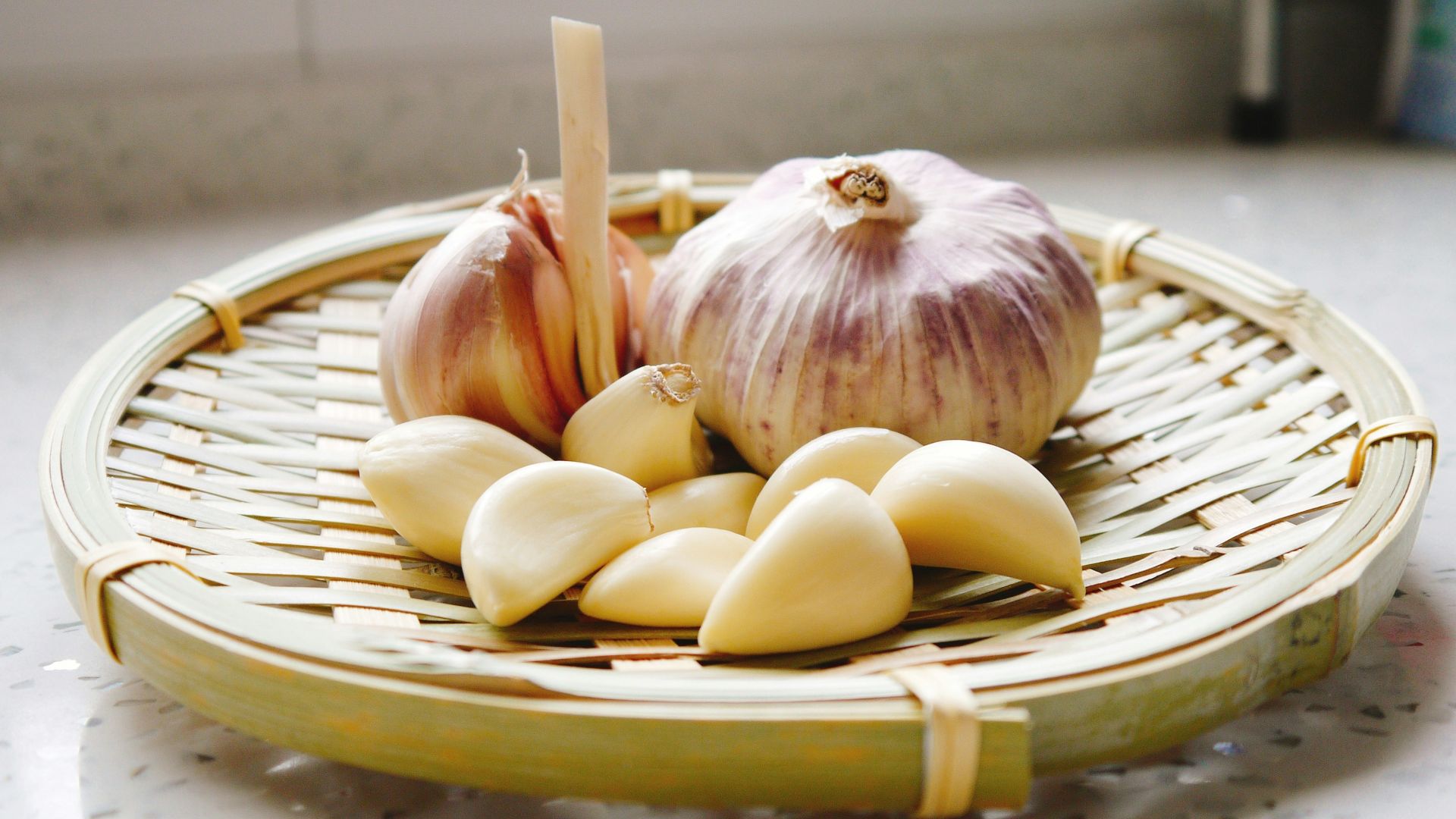 a basket of garlic and garlic bulbs on a counter
