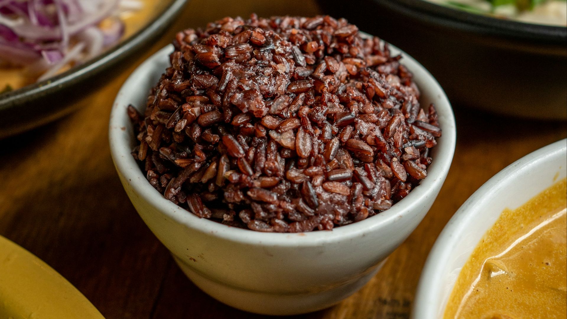 a wooden table topped with bowls of food
