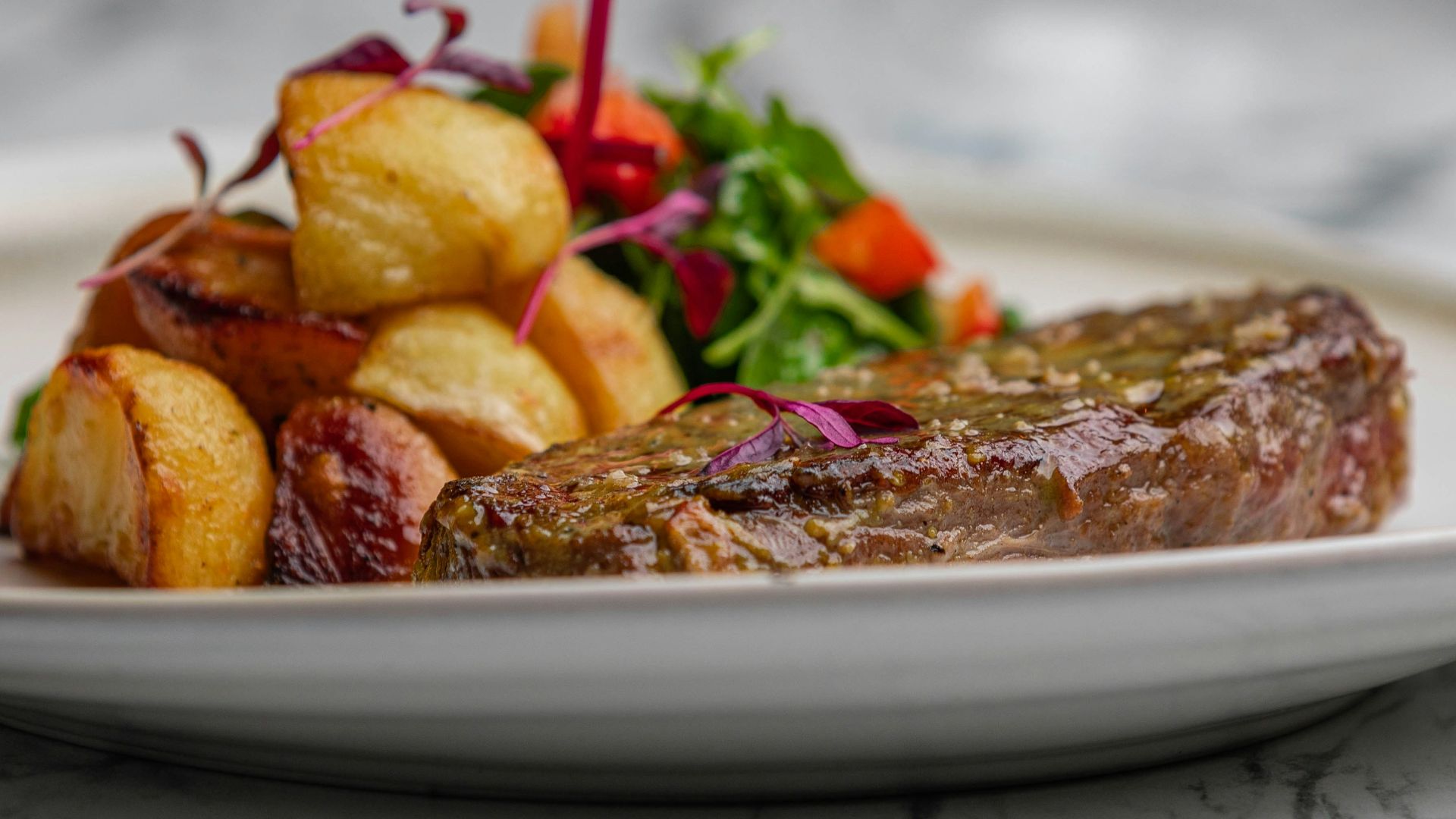a white plate topped with meat and potatoes