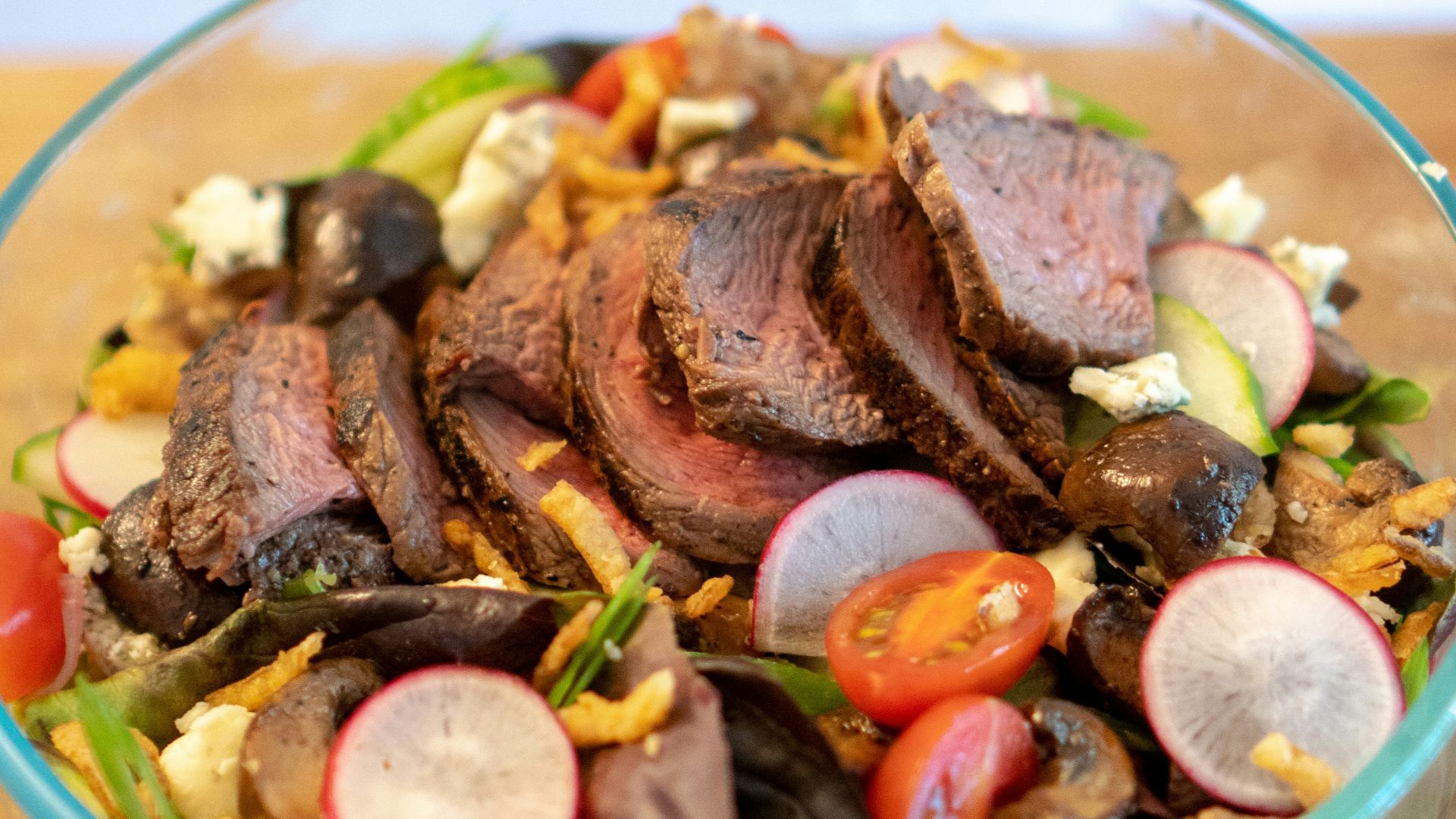a glass bowl filled with meat and vegetables