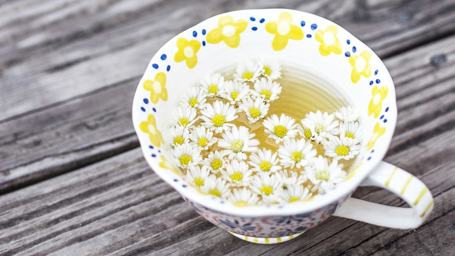 white and yellow cup with flowers on table