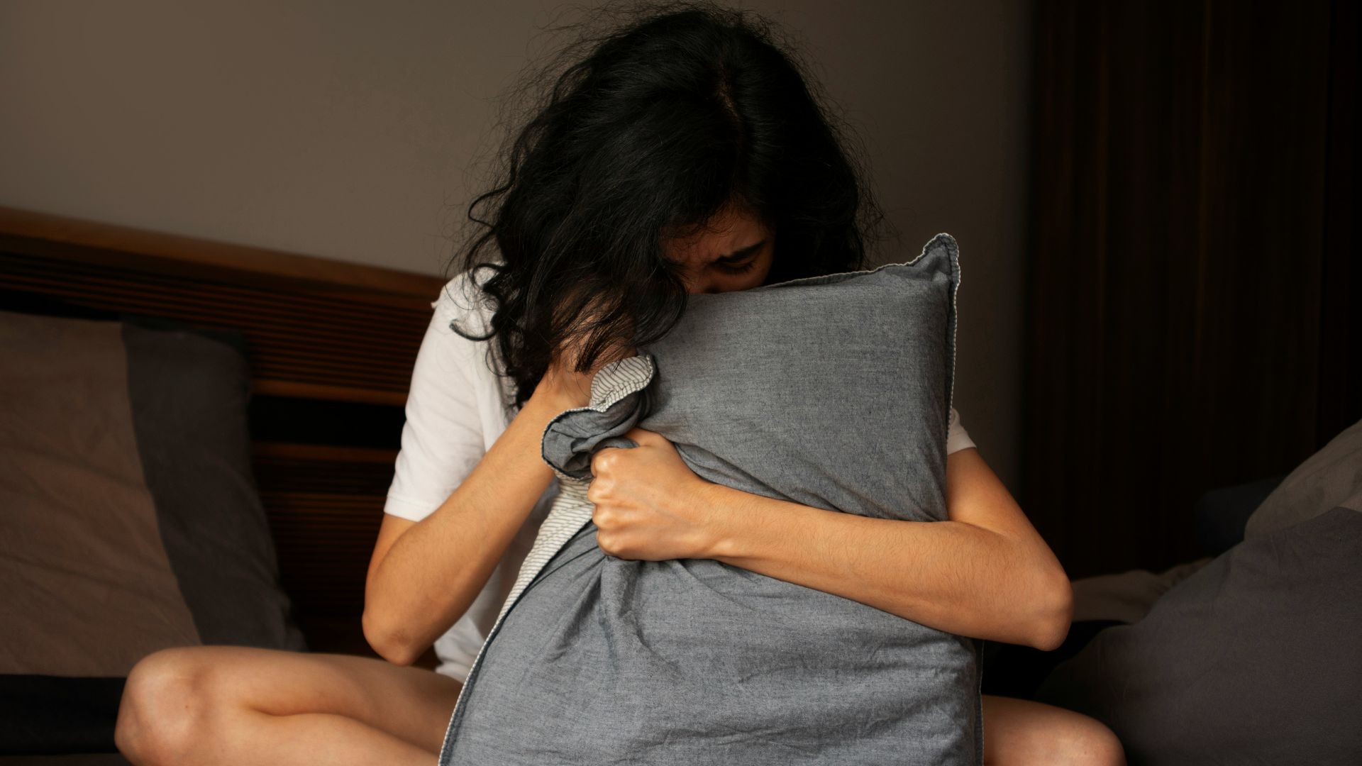 A woman sitting on a bed holding a pillow