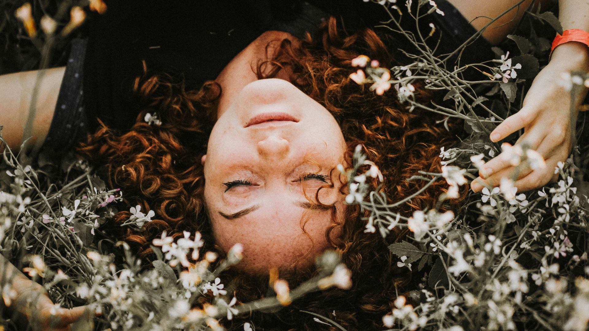woman lying on flowers during daytime