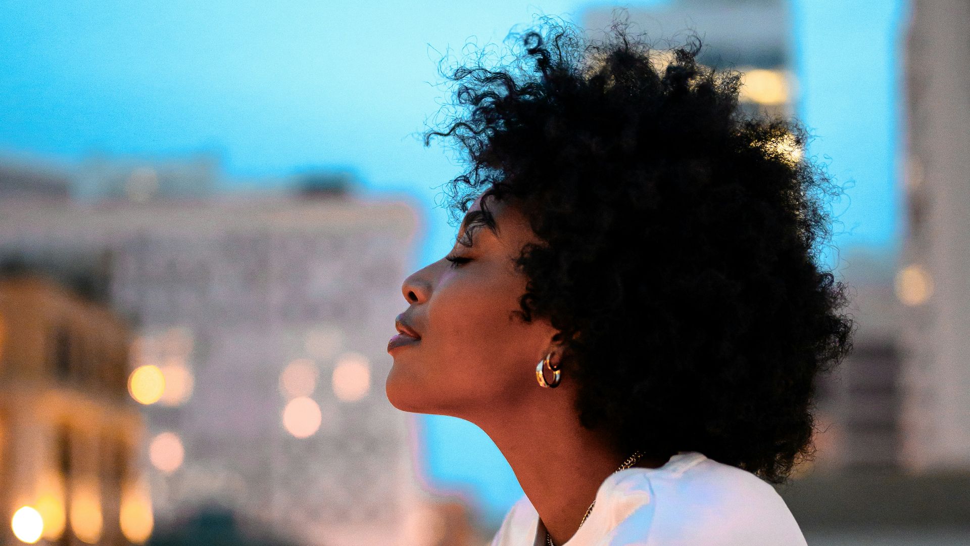 woman in white collared shirt looking at the city during night time