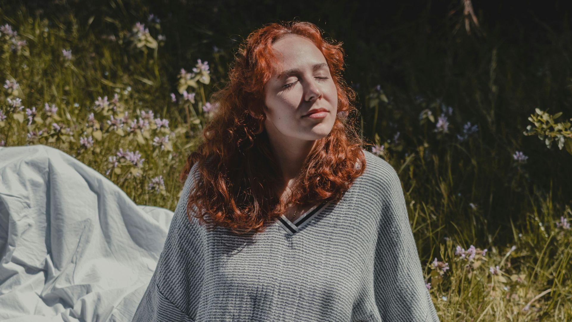 woman in gray sweater sitting on white textile