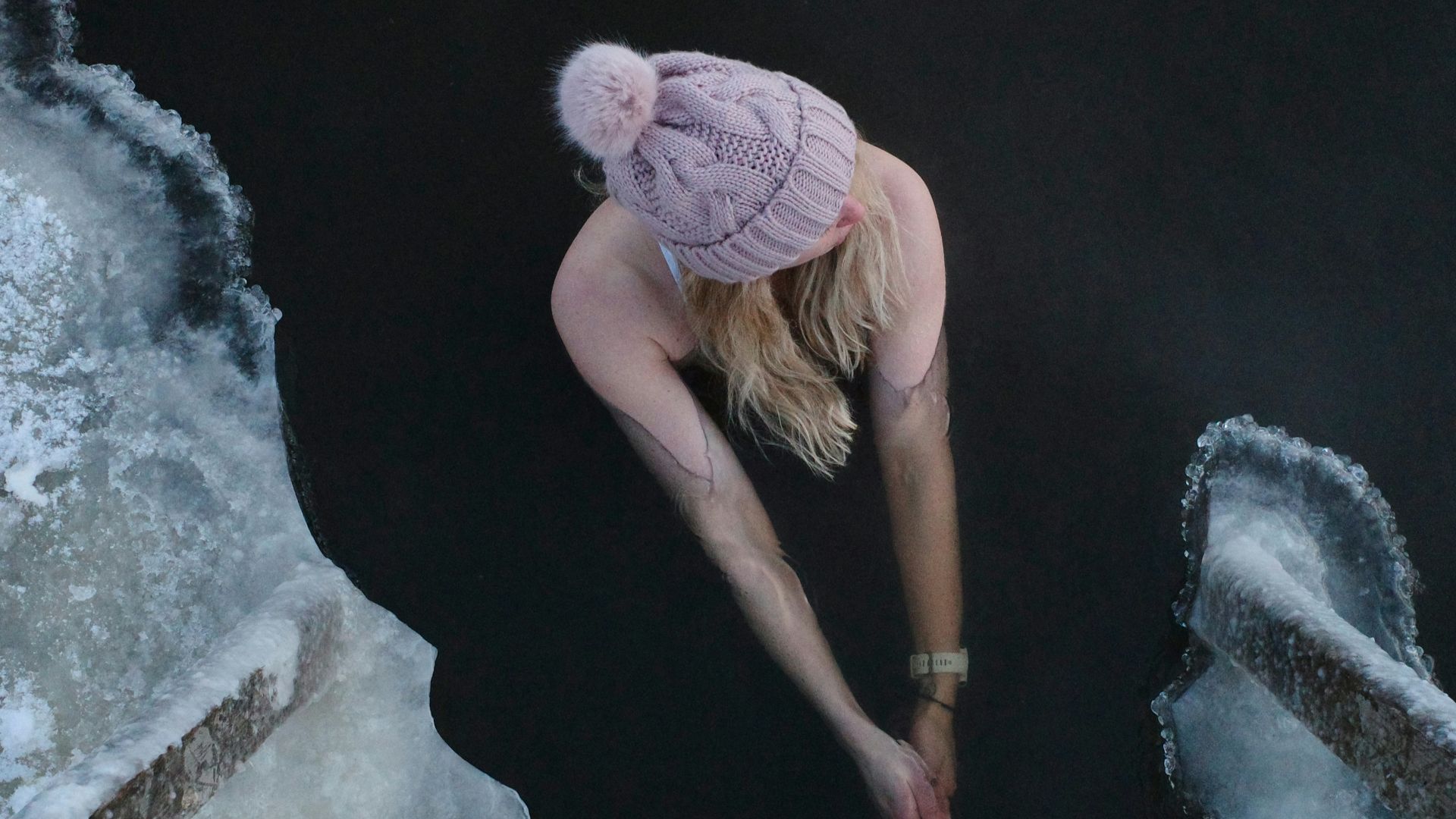 woman in pink knit cap and brown shirt climbing on rock