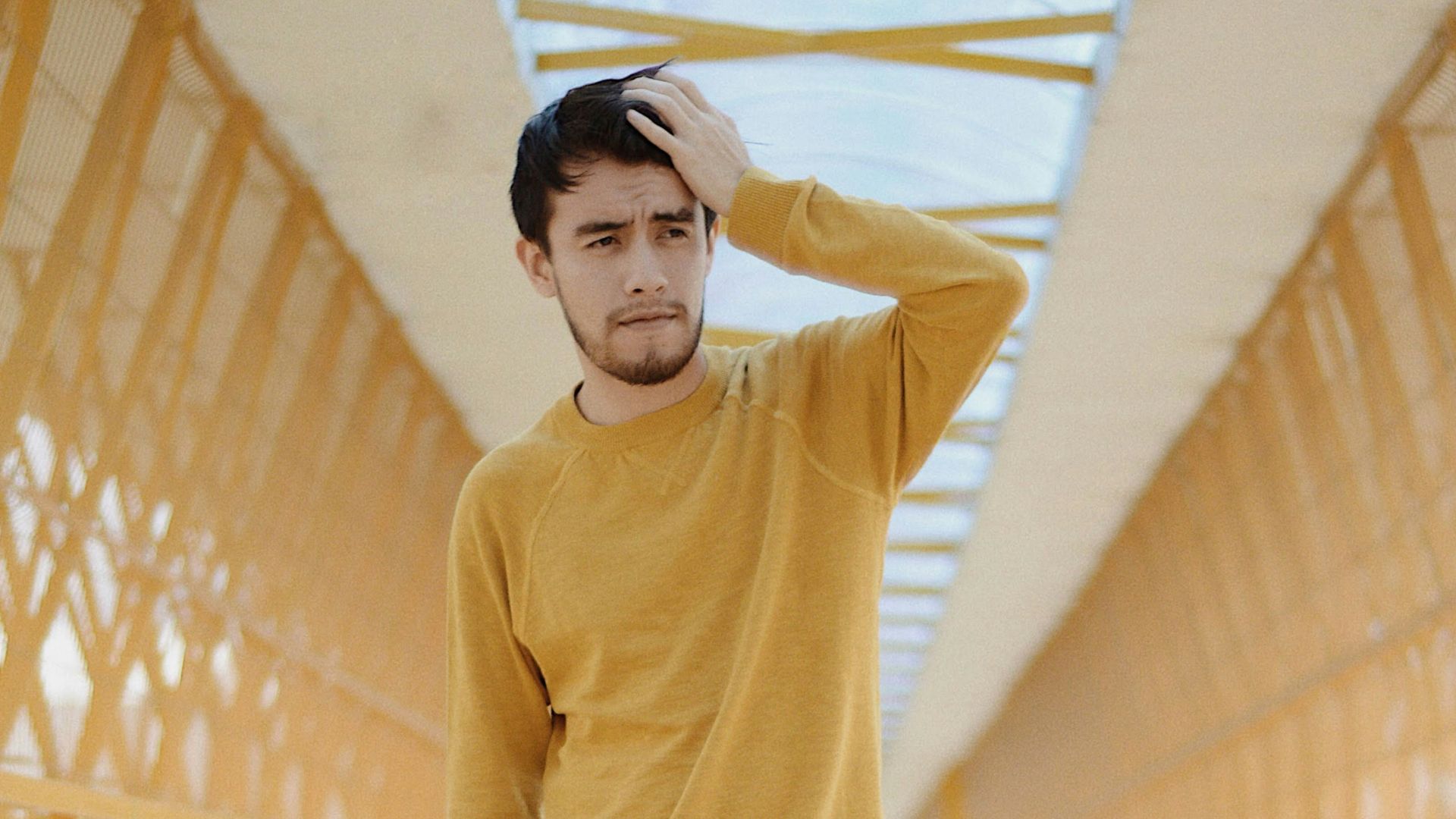 man standing on bridge while touching his head