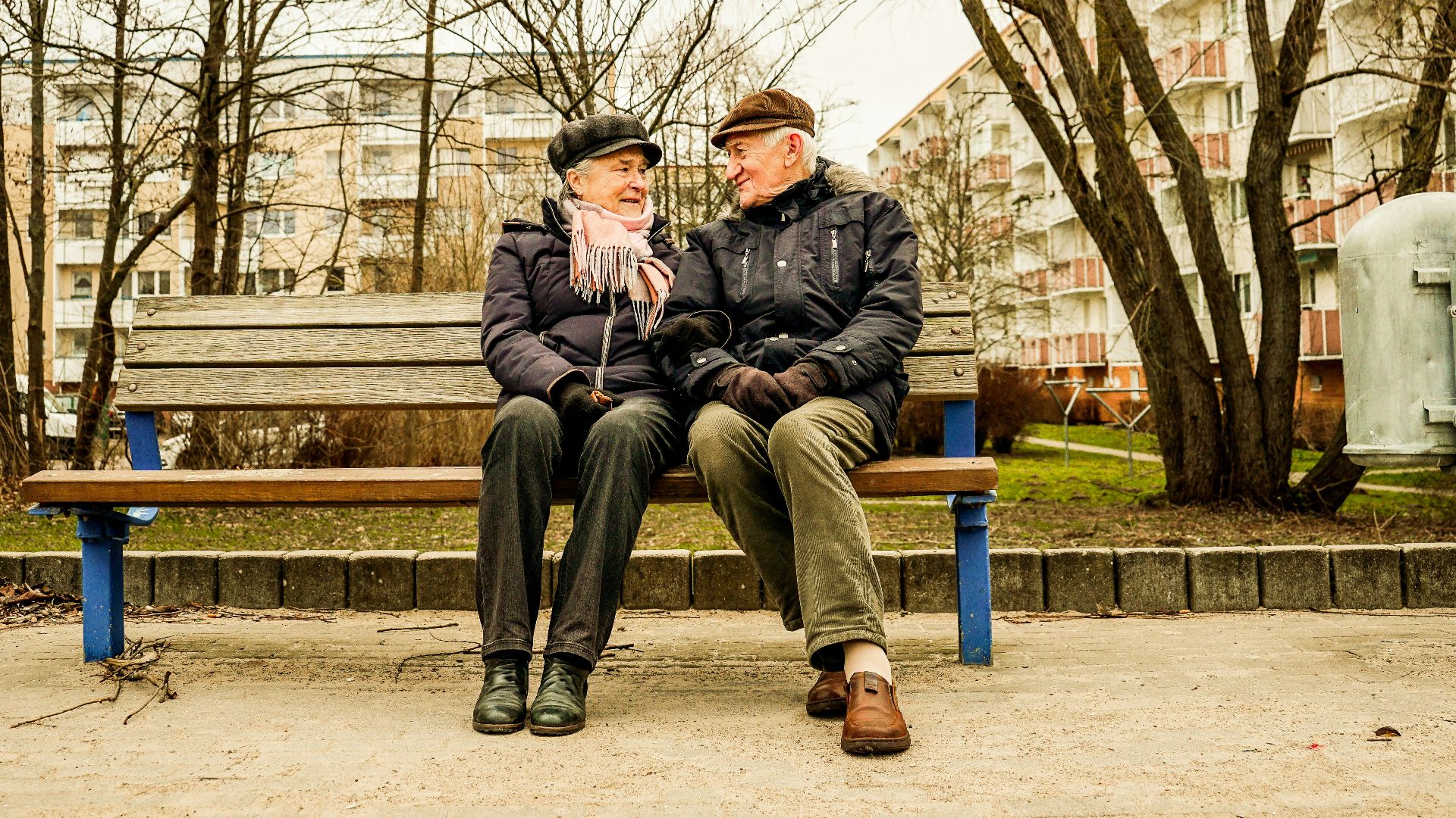 Elderly couple happily sitting on a bench together.