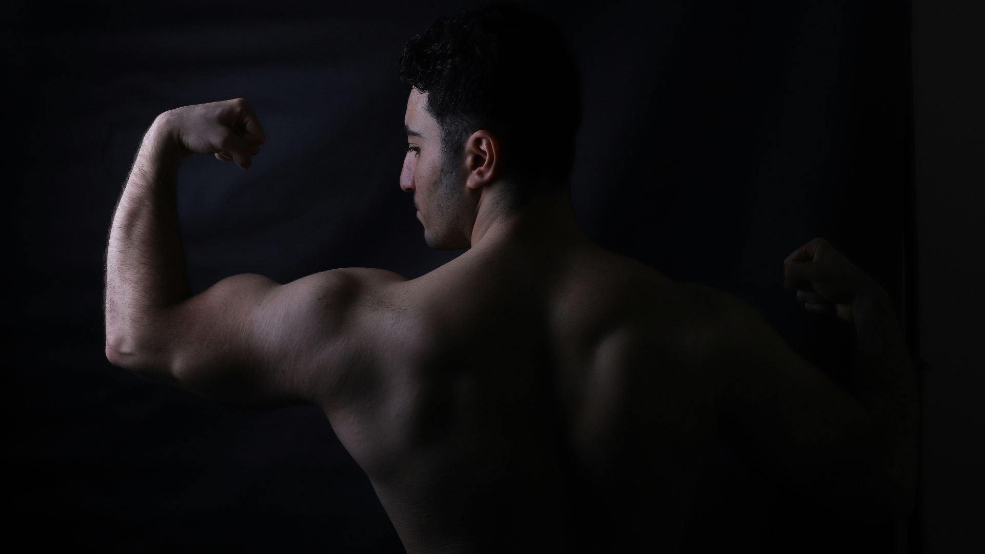 A bodybuilder flexes his biceps for the camera.