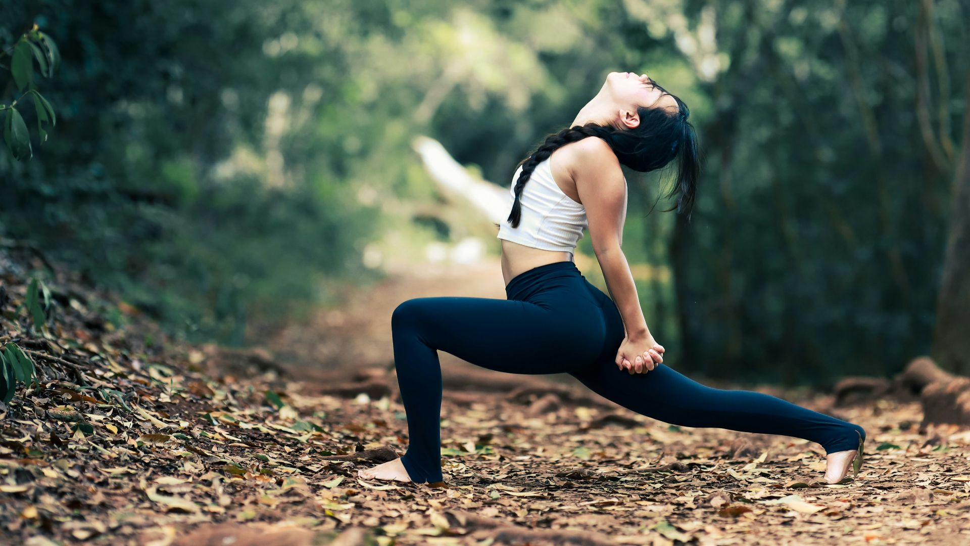 woman in white shirt and black leggings sitting on brown dirt road during daytime