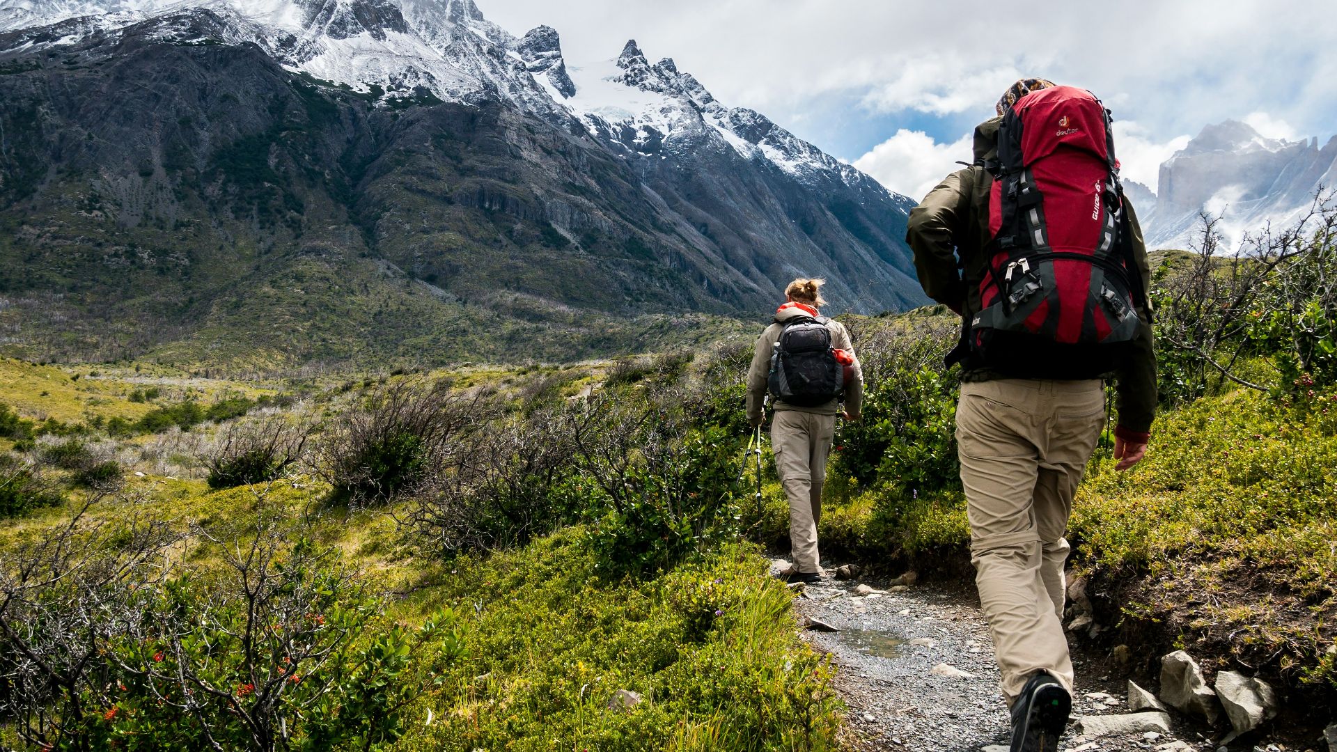 two person walking towards mountain covered with snow