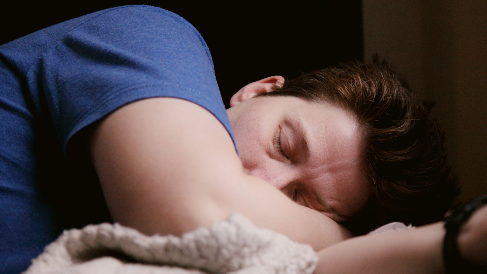 woman in blue shirt lying on bed