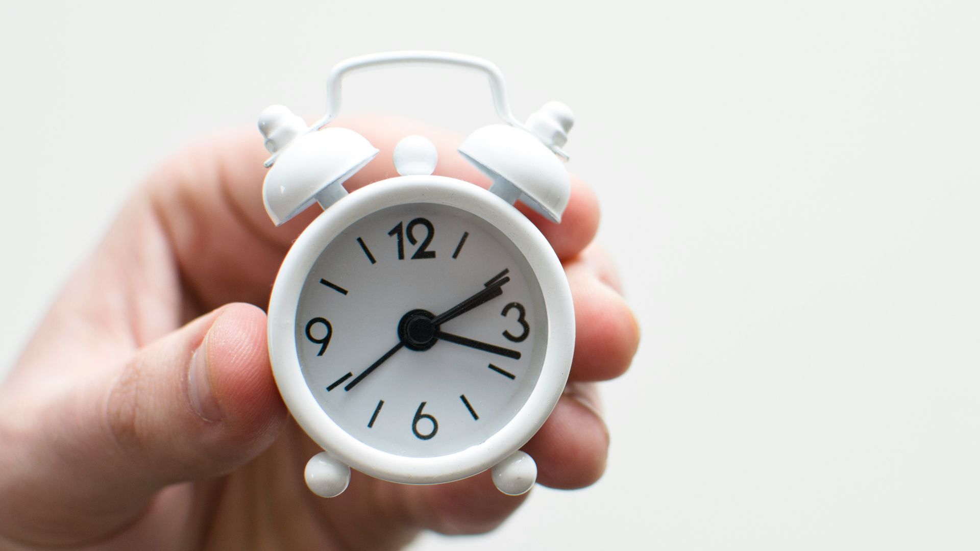person holding white mini bell alarmclock