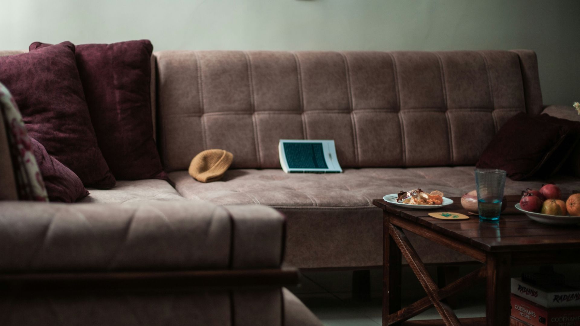 A sectional sofa with pillows and a tablet on it.