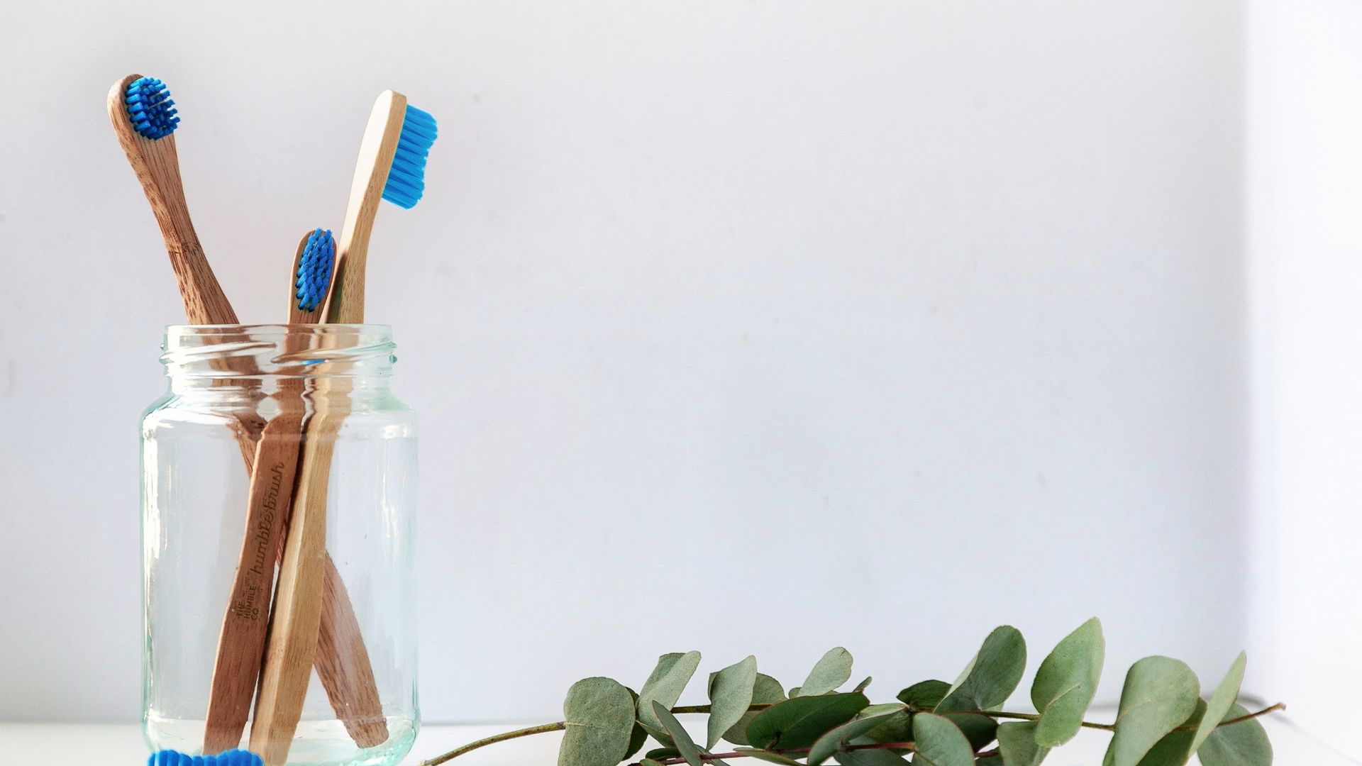 blue and white toothbrush in clear glass jar