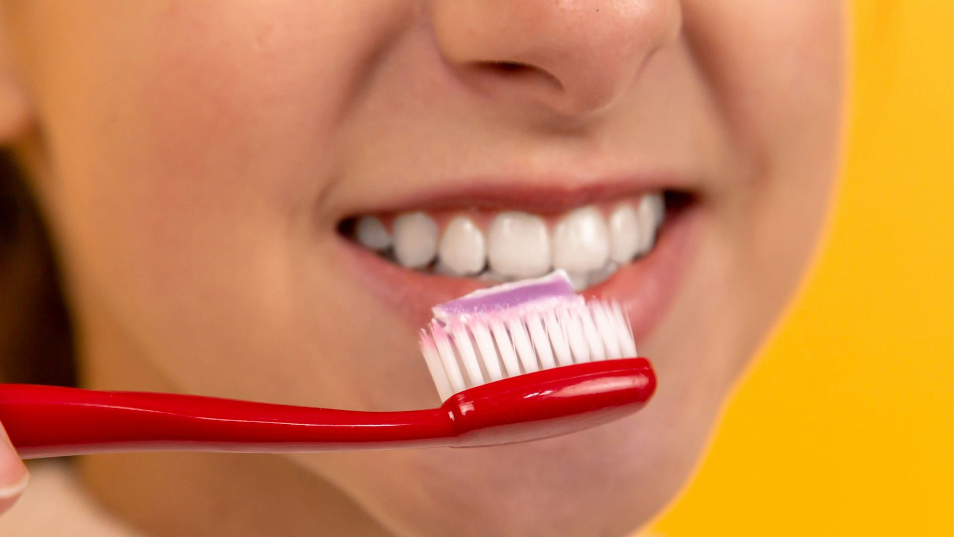girl with red and white toothbrush in mouth
