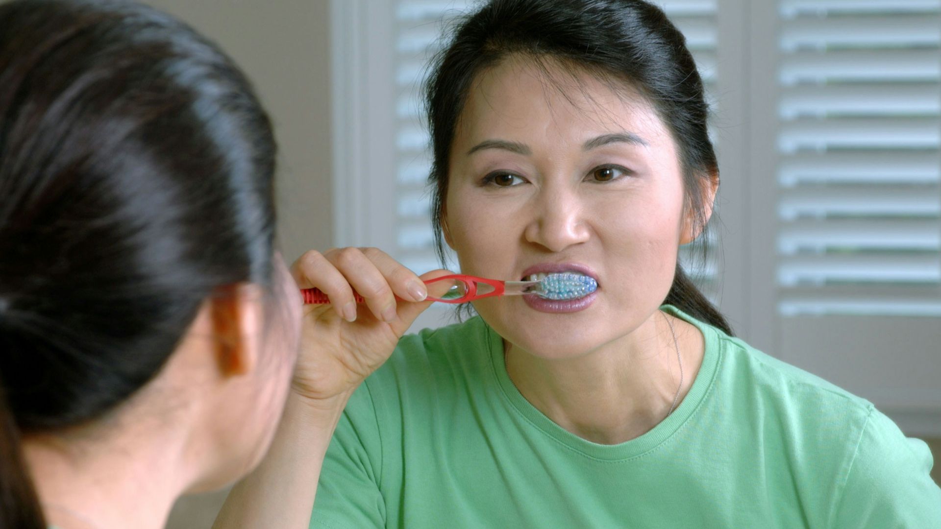 woman in green crew neck shirt holding red lollipop