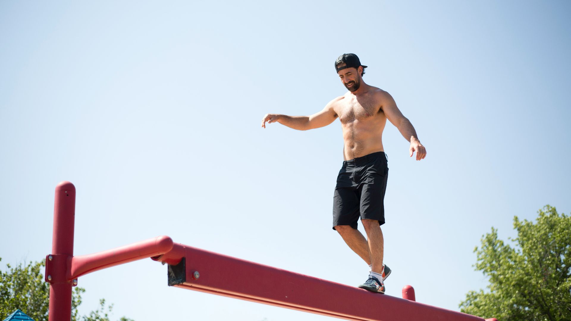 man wearing black shorts walking on red metal beam