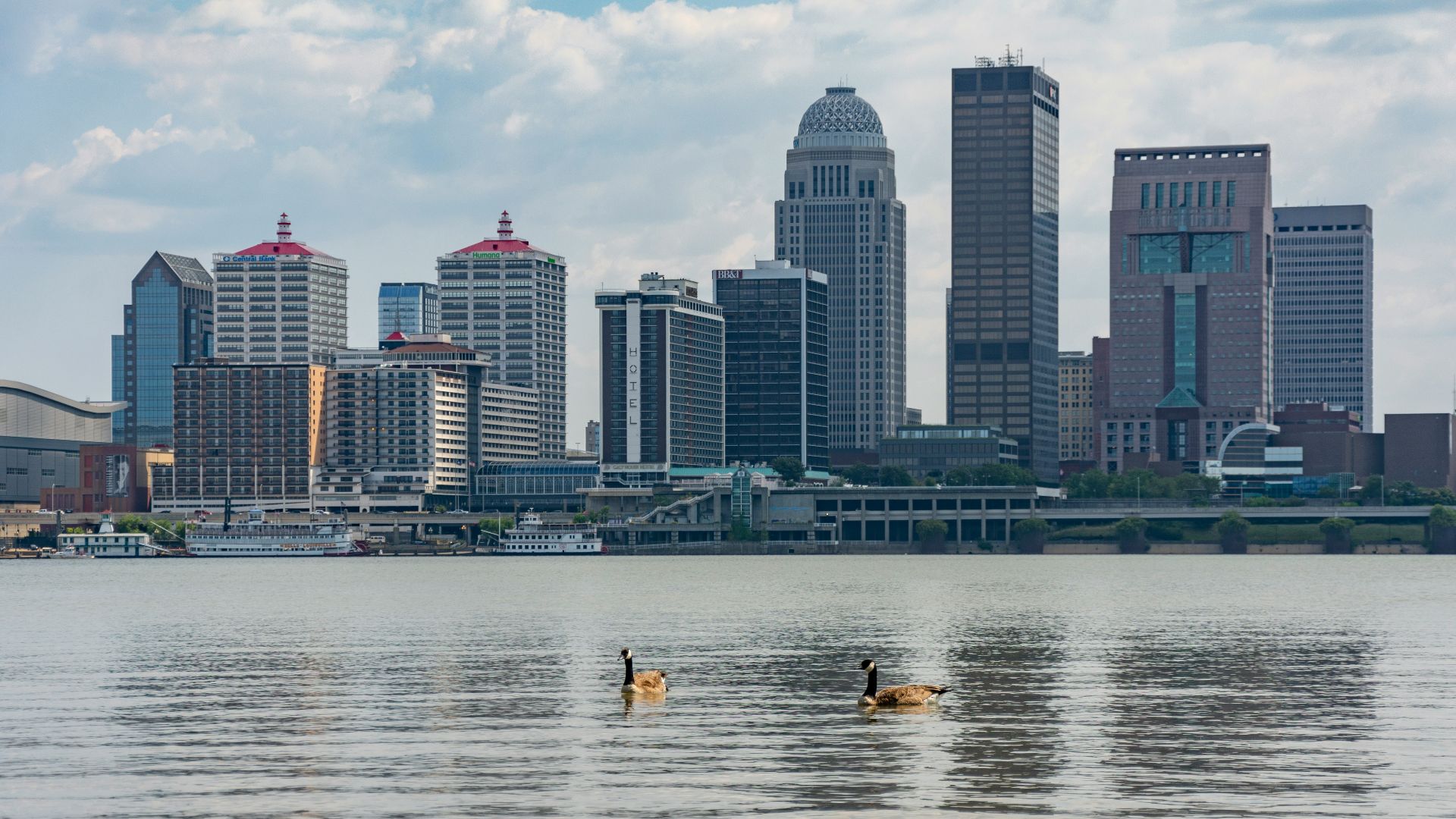 The louisville skyline is seen over the river.
