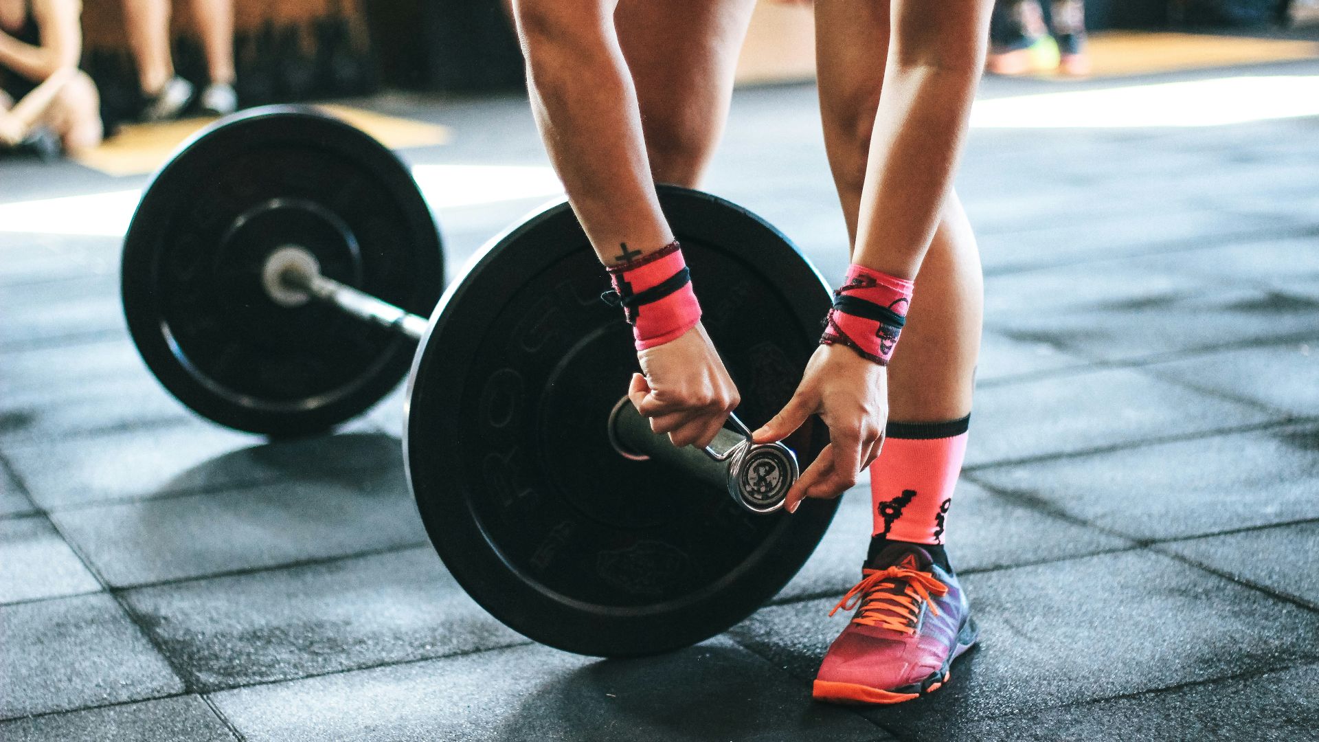 person locking gym plates on barbell