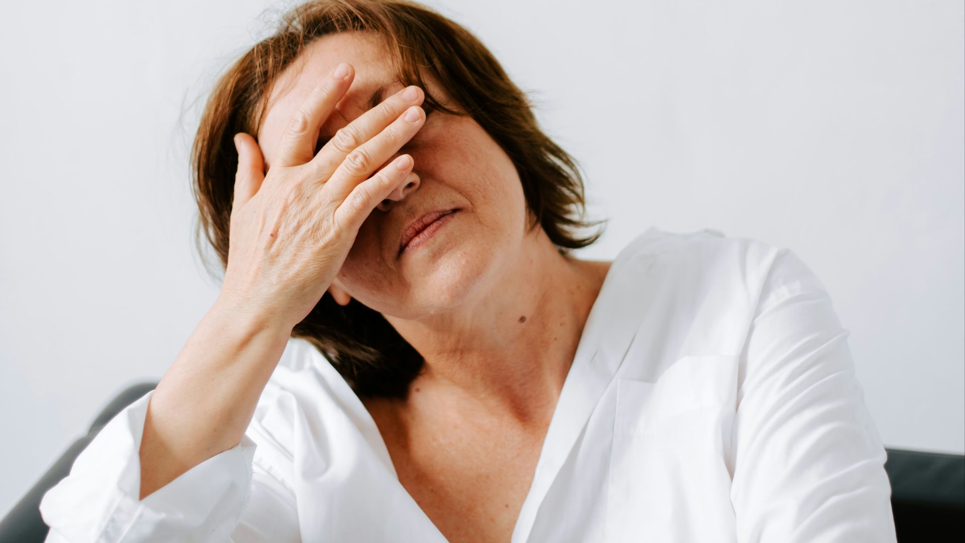 a woman sitting on a couch holding her hands to her face