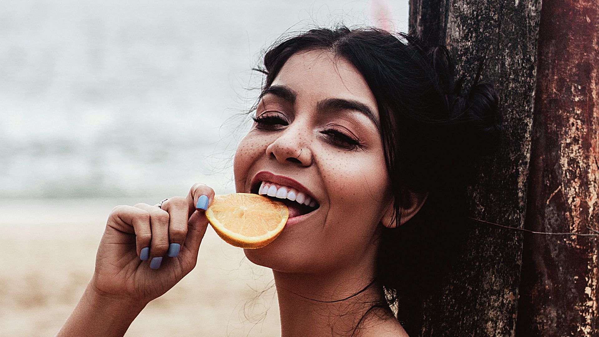 a woman sitting on the beach brushing her teeth