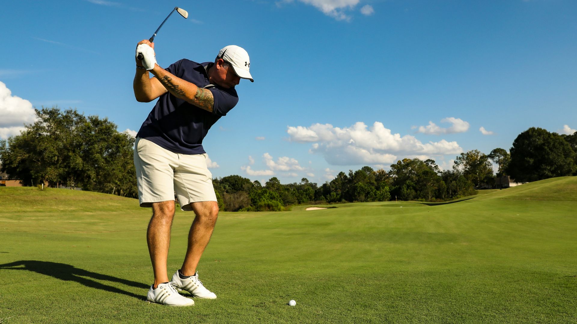 man in black shirt and white shorts playing golf during daytime