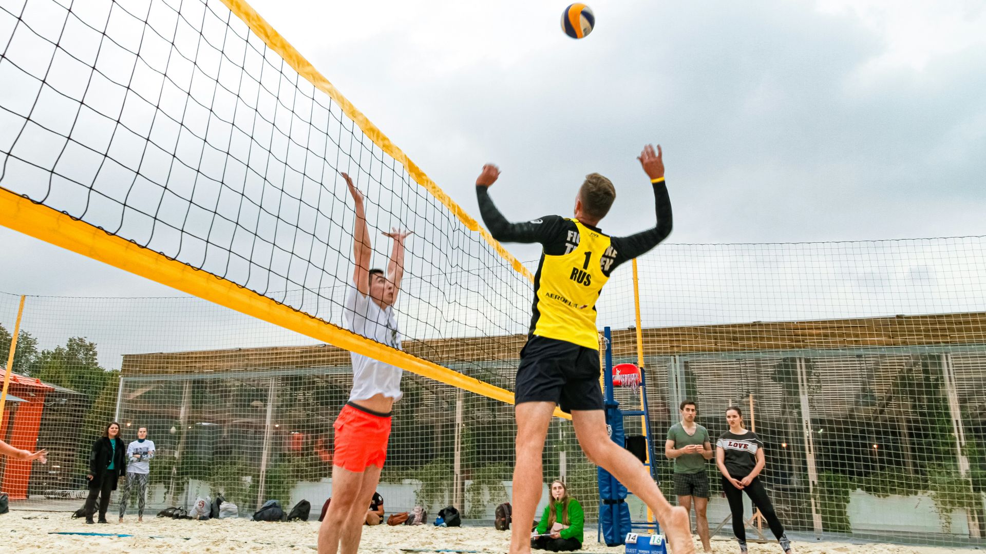 man wearing yellow and black long-sleeved shirt playing volleyball