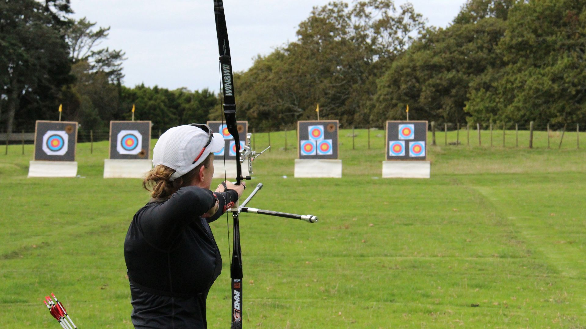 a woman is practicing archery in a field