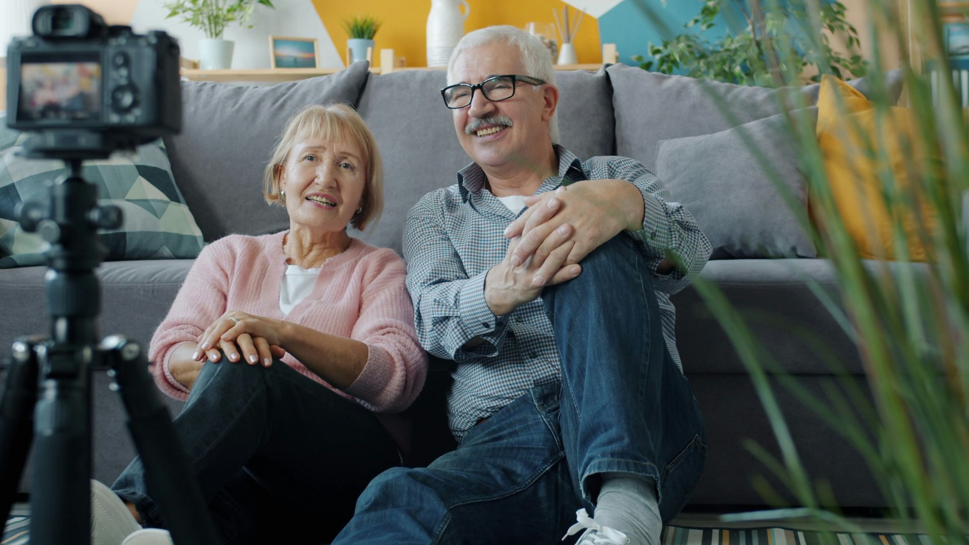 Elderly couple smiling at camera in-home video camera setup.