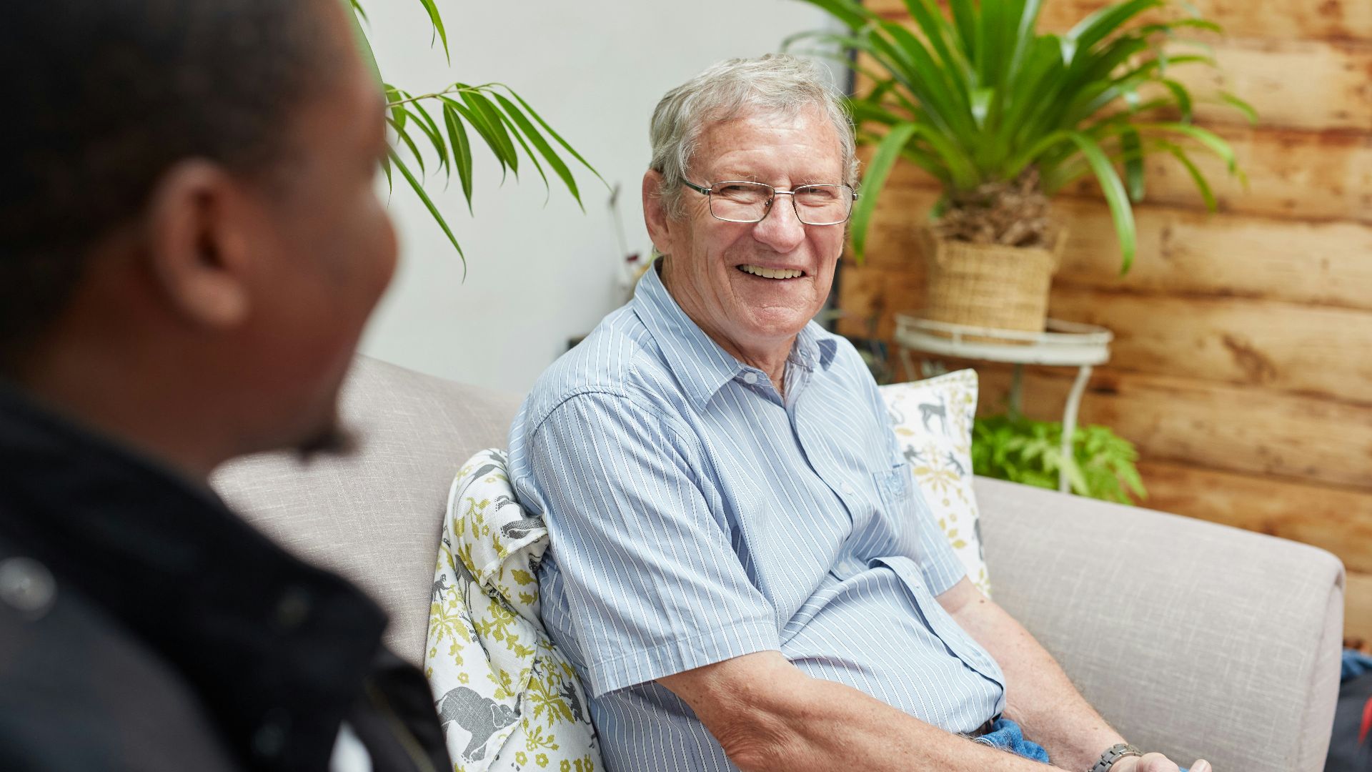 a man sitting on a couch talking to another man