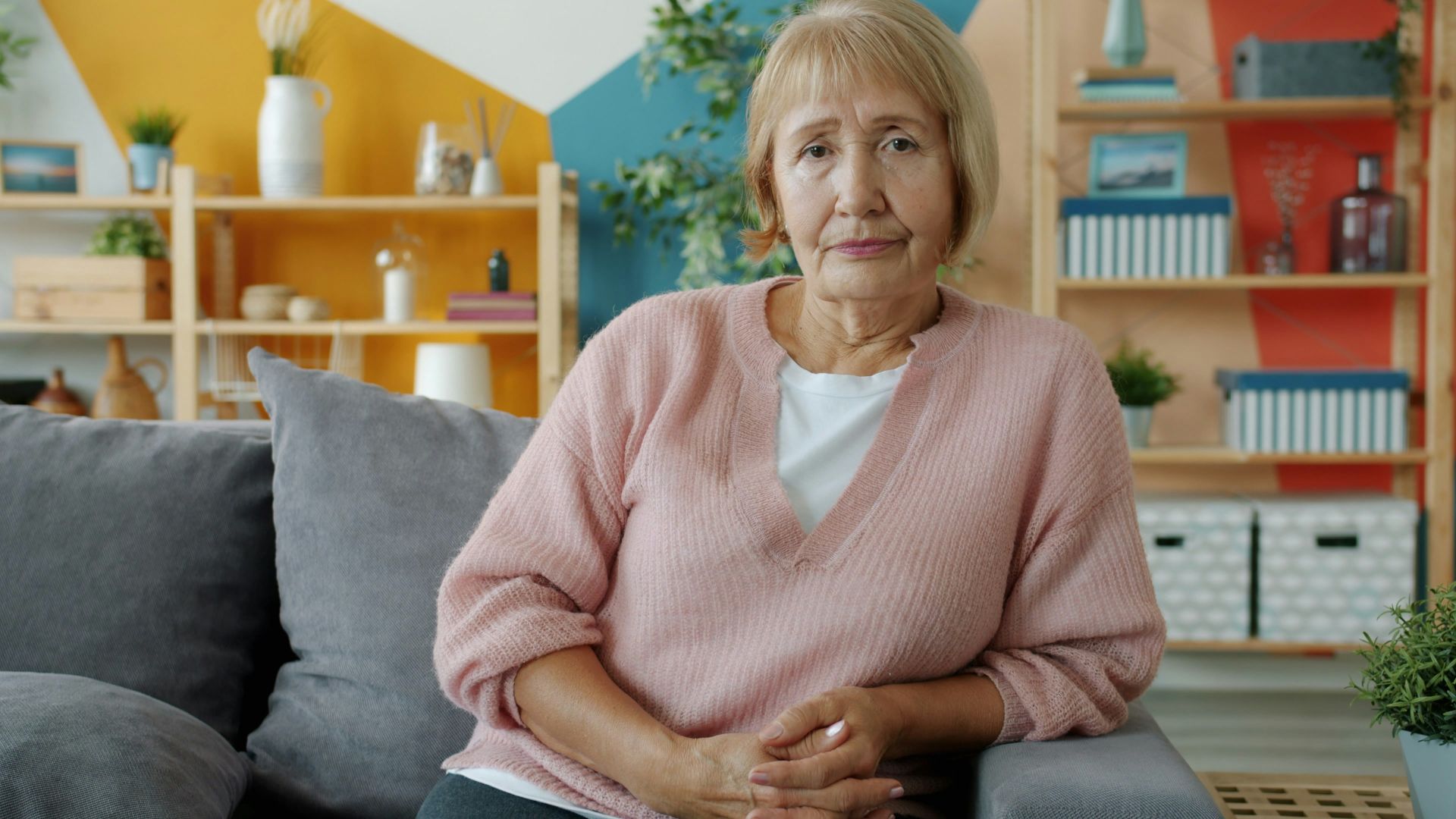 Elderly woman sitting on a couch in a living room.