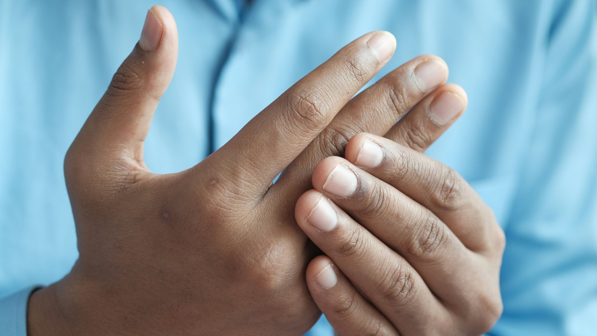 person in blue shirt showing left hand