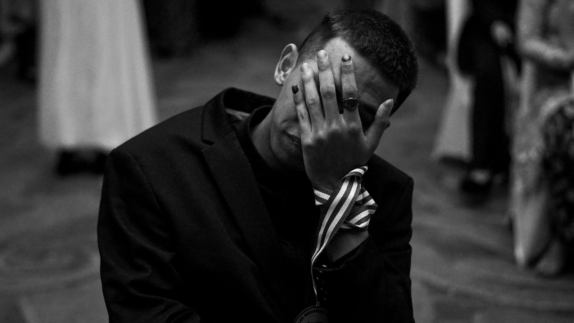 Man in suit covers face with hand