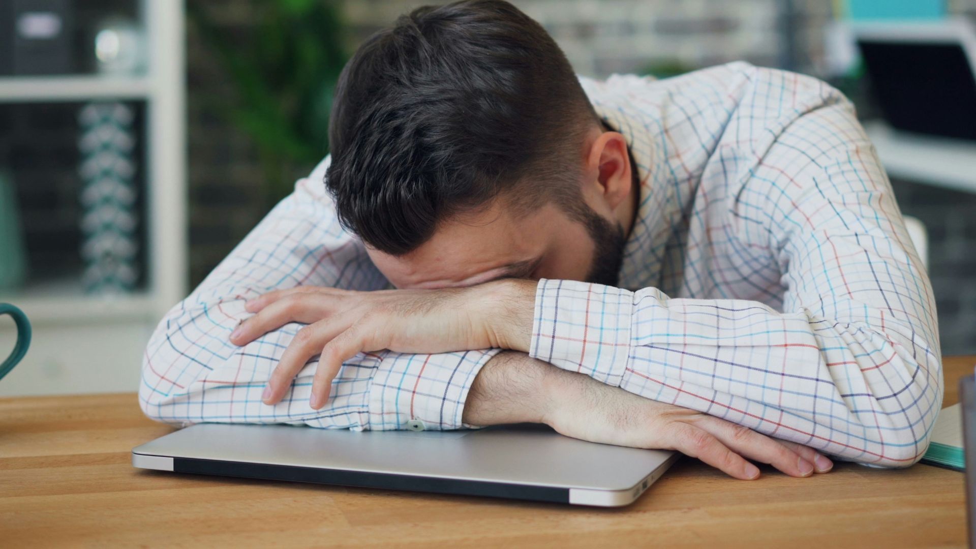 a man sitting at a desk with his head in his hands