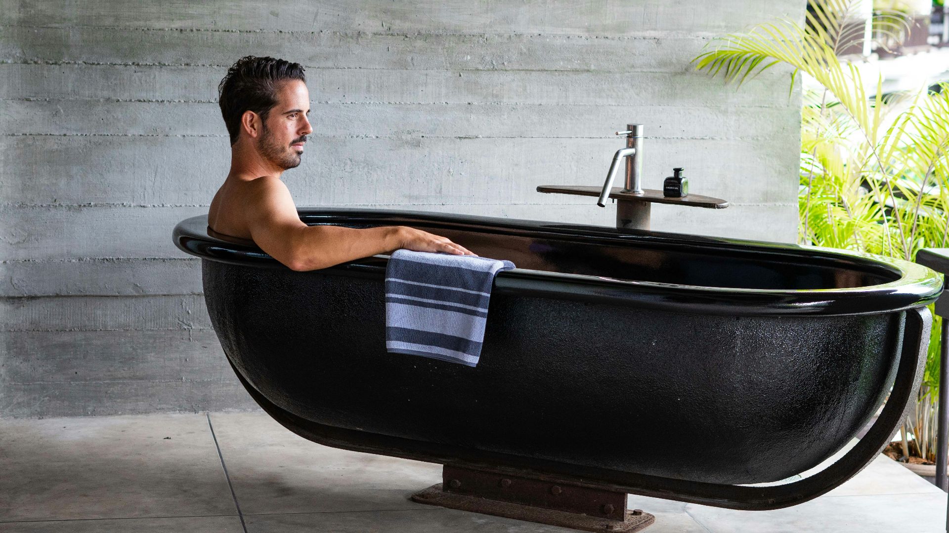 A man sitting in a bathtub with a towel on it