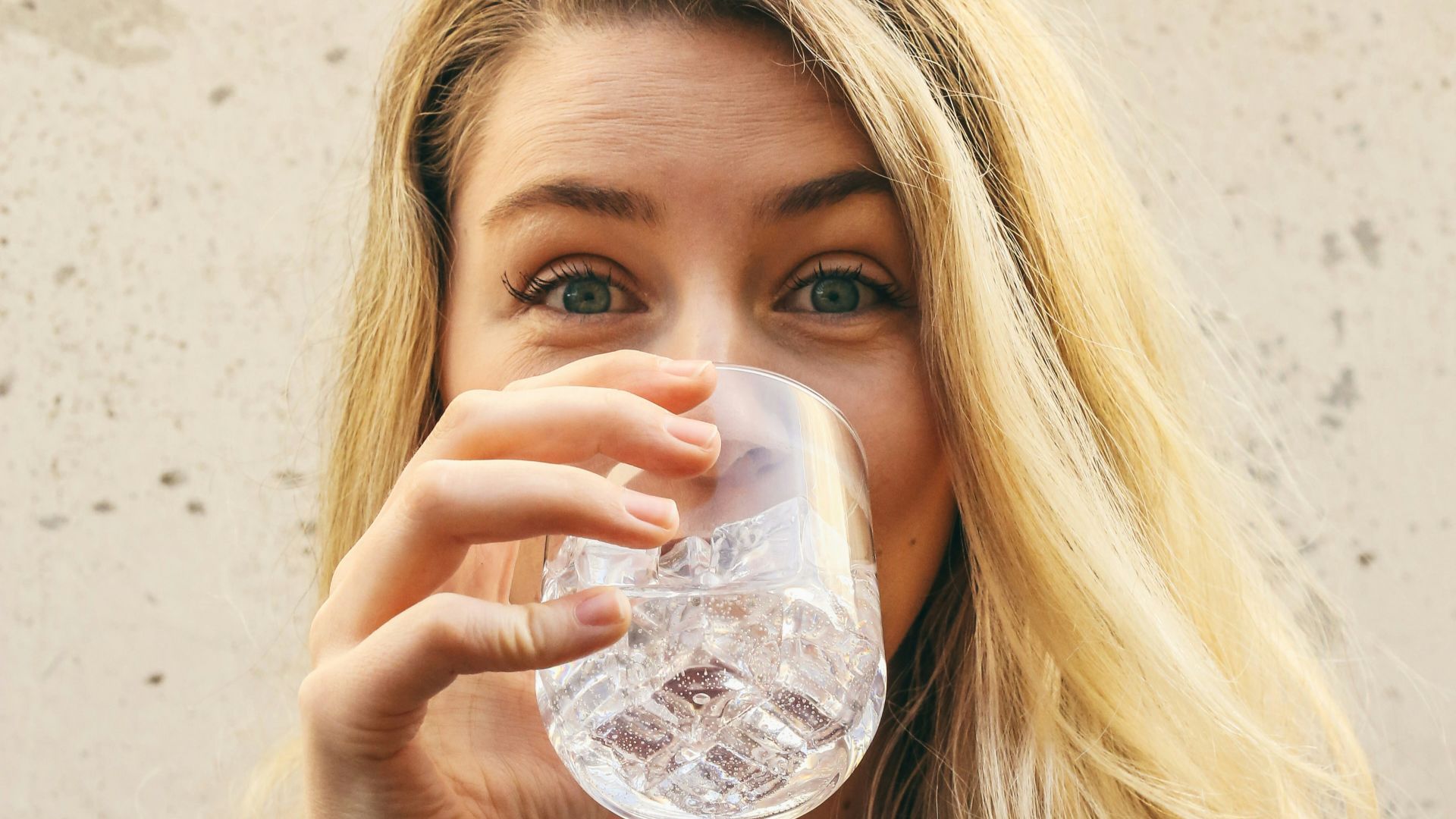 woman in white crew neck shirt drinking water
